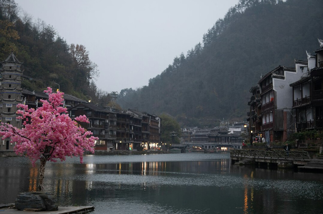 Calm river reflecting an old town and trees