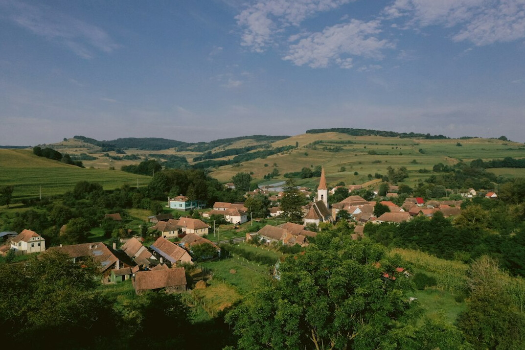 Rolling green hills with a small village in the distance