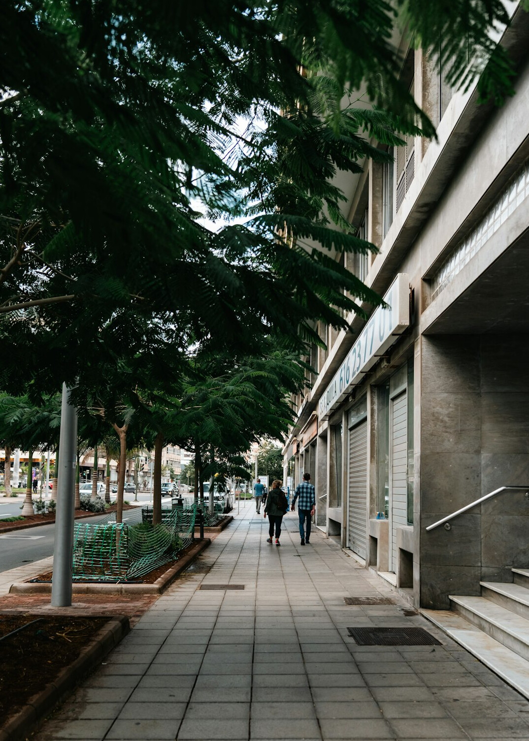 People walking past a modern building on a city sidewalk